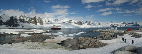 Antarctic tour boat, with visitor on land in foreground.