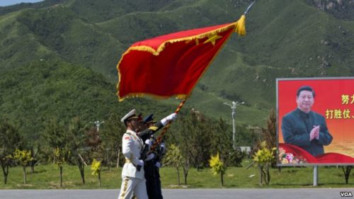 China flag waves in foreground, Xi Jinping on billboard in background