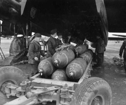 British soldiers loading 1,000 pound bombs into an airplane during World War II.