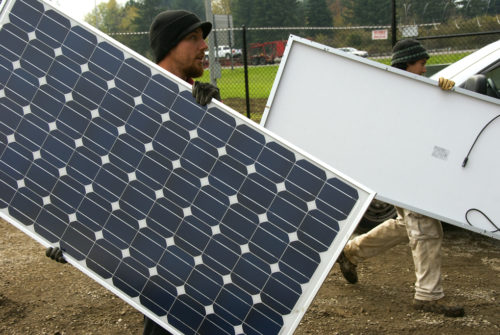 Men carrying solar panels for installation.