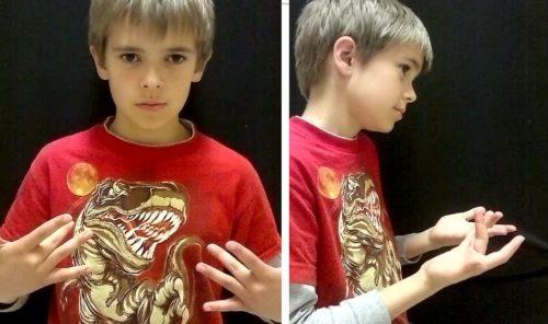 A boy shows how to say, "What's up?" in sign language.