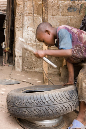 A child repairs a tire in The Gambia.