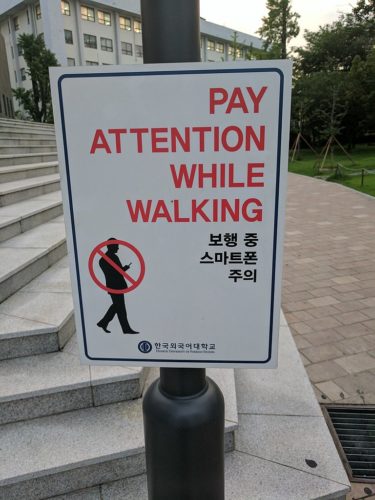 Sign saying "PAY ATTENTION WHILE WALKING" in Seoul, Korea.