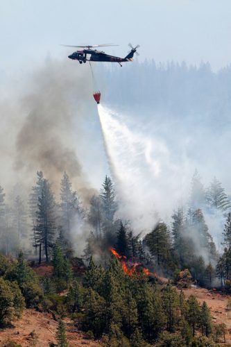 A California National Guard UH-60 Blackhawk crews drop water on the Ponderosa wildfires near Redding, Calif.