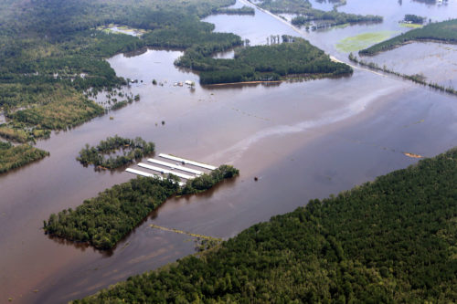 Flooded CAFO with a visible stream of pollution on the water's surface.