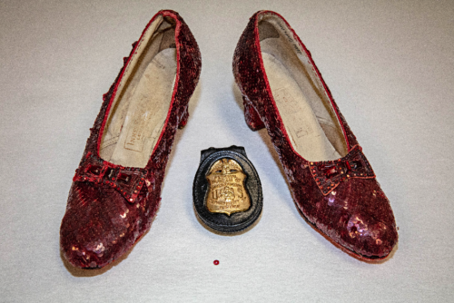 The recovered ruby slippers, along with an FBI badge. The single sequin shown here was found at the crime scene at the Judy Garland Museum, from which a pair of Ruby Slippers went missing in 2005.