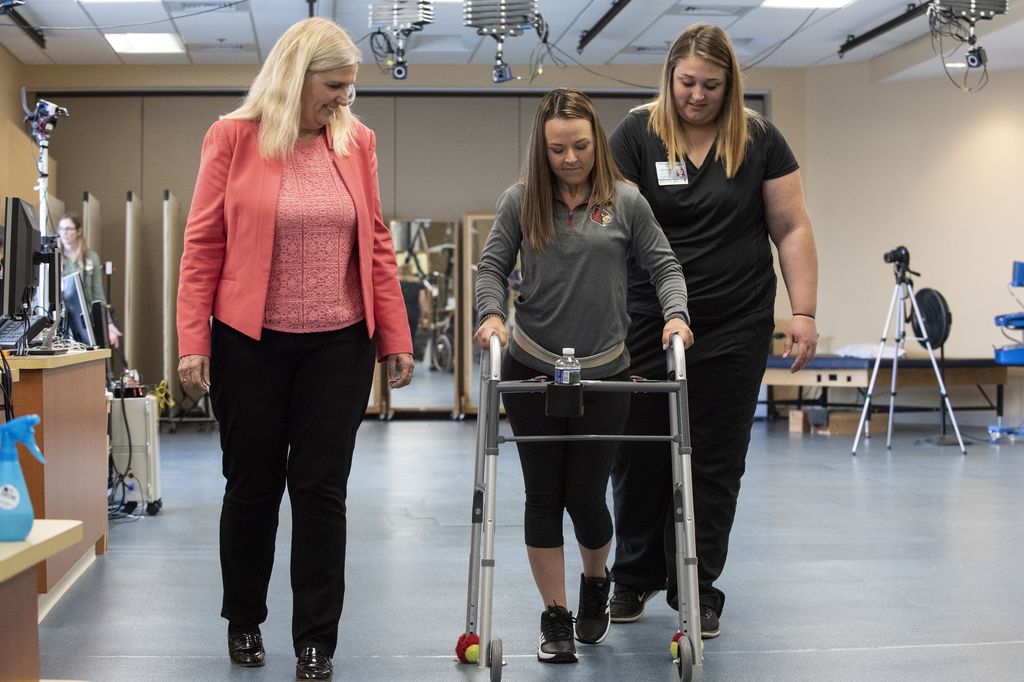Paralyzed woman walks using a walker.