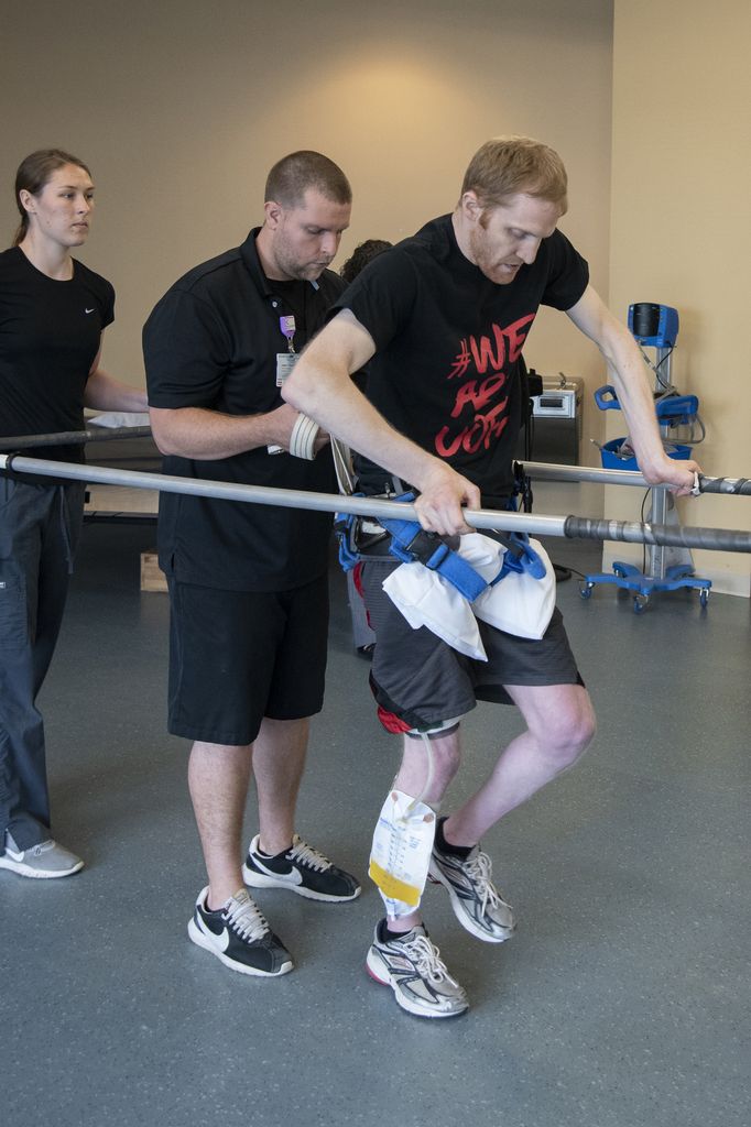 Paralyzed man walks supporting himself on a frame.