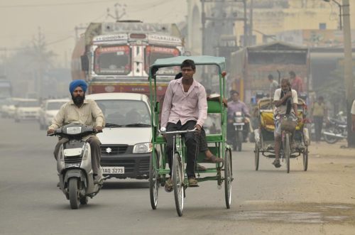 A variety of vehicles on a hazy and busy street. Pic by Neil Palmer (CIAT). GV of traffic in Sangrur, SE Punjab, India.