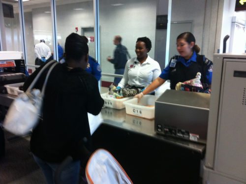 Security screeners check trays at a security checkpoint