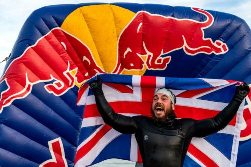 Ross Edgley holds a British flag behind him at the end of his 157 day swim around the UK.