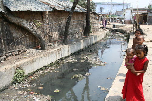 Children stand beside the main drain of Malgudam community. Each morning, many children from the community come to the drain together to defecate and urinate.