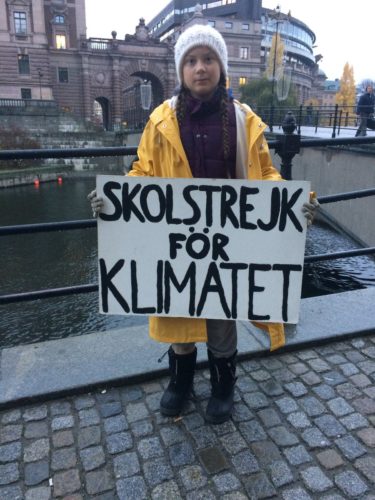 Greta holding sign that says, "School Strike for Climate".