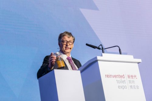 Bill Gates holds a jar holding human feces.