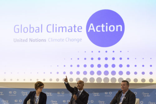 04.12.2018 - The Future of our Food in the Face of Climate Change. Speaker with finger raised under sign saying 'Global Climate Action'