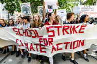 Students marching and chanting, holding a sign saying "School Strike for Climate Action".
