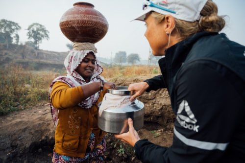 Ultra runner and water campaigner, Mina Guli helps a local woman collect water near Dahod, India during the #RunningDry Expedition, on 1 December 2018