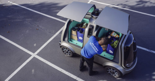 Man loading Nuro's R1 self-driving delivery vehicle.