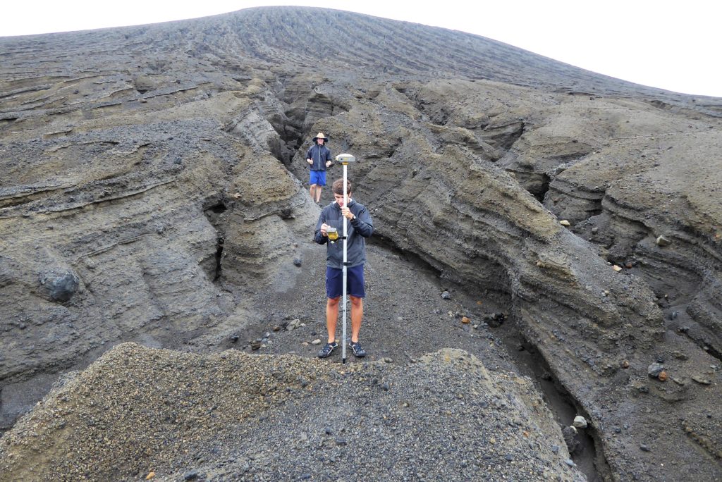 Students stand in a deeply eroded gully, taking a measurement.