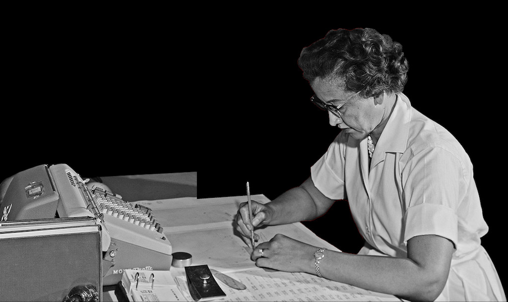 Katherine Johnson working at a desk with a mechanical calculating machine in front of her.