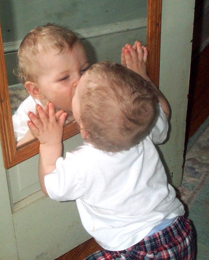 Baby kissing mirror image.