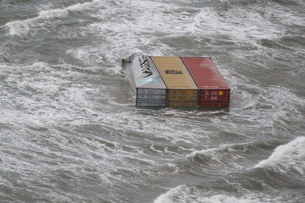 Three containers, one damaged, float in the water.