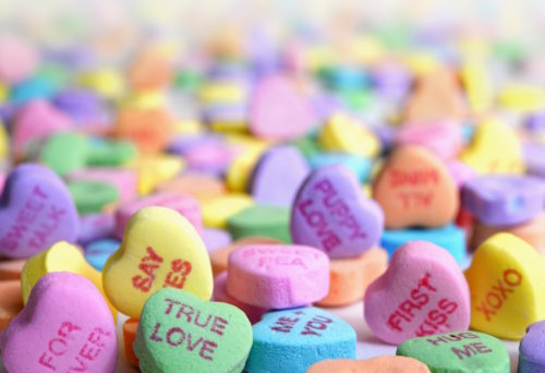 Close up picture of Sweethearts candies, with phrases such as "True Love", "Say Yes", and "Puppy Love" visible.