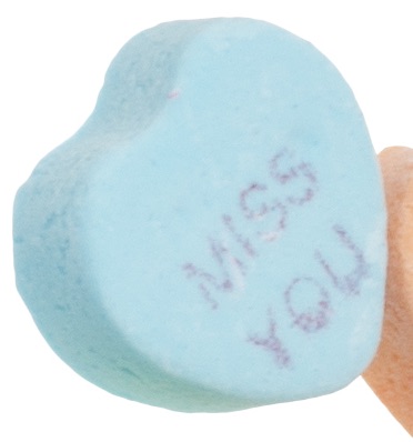 Closeup of a Sweetheart candy that says "Miss You".