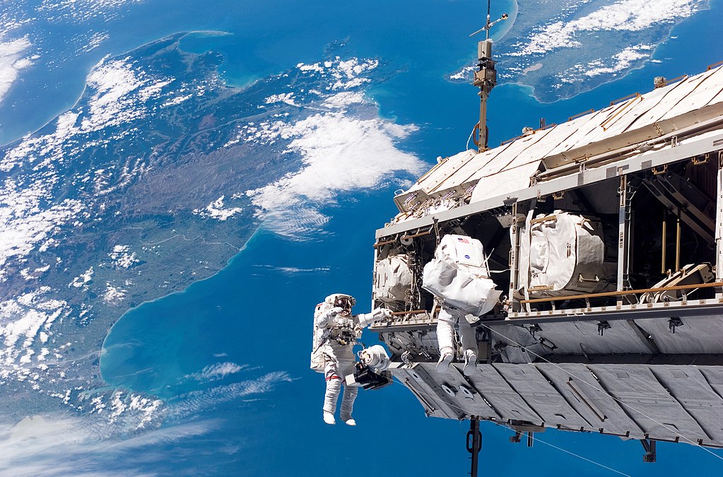 Backdropped by a colorful Earth, astronaut Robert L. Curbeam, Jr. (left) and European Space Agency (ESA) astronaut Christer Fuglesang, both STS-116 mission specialists, participate in the mission's first of three planned sessions of extravehicular activity (EVA) as construction resumes on the International Space Station.