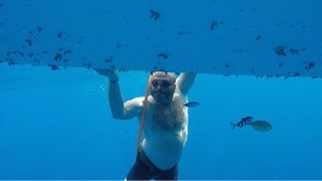 Lee Spencer cleaning barnacles from the bottom of his rowboat.