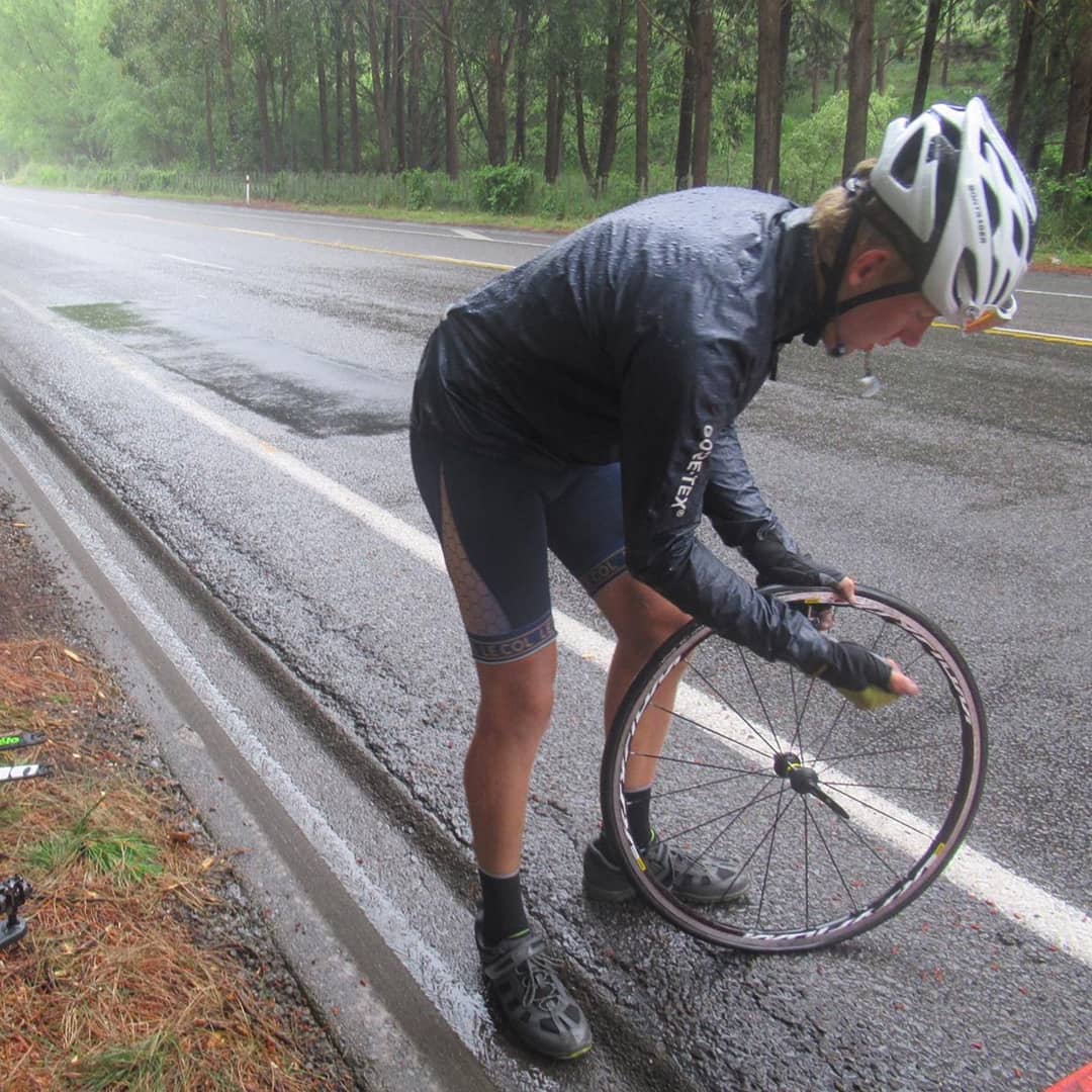 Charlie fixing a flat tire by the side of the road.