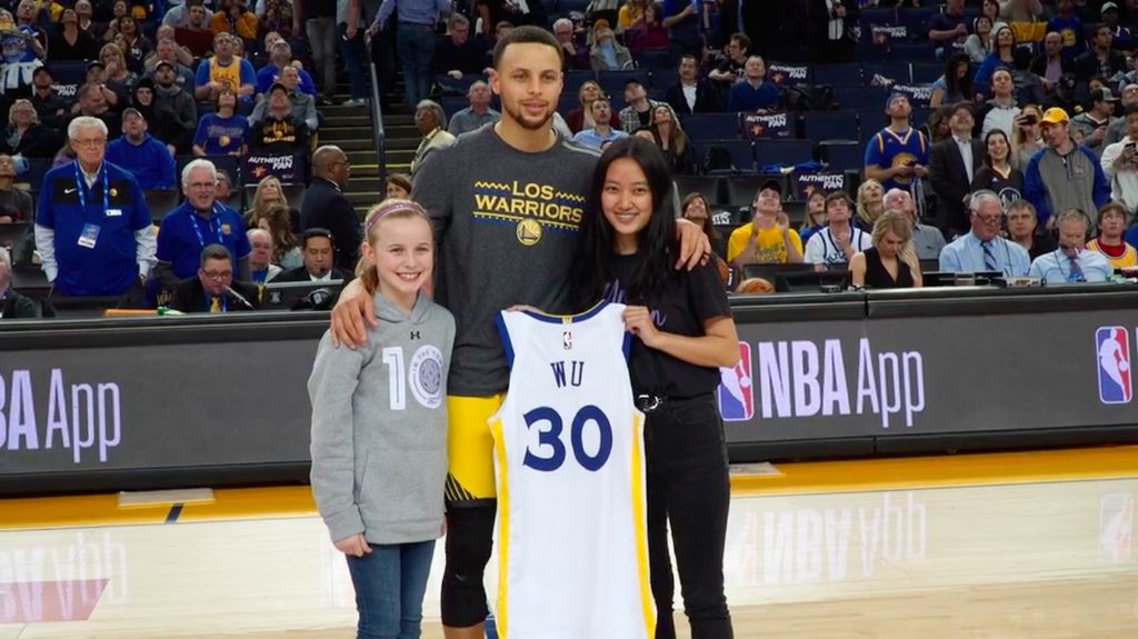 Riley Morrison, Stephen Curry, and Vivian Wu stand at center court.