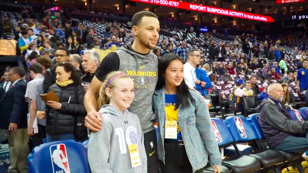 Riley Morrison, Stephen Curry, and Vivian Wu stand by the sidelines.