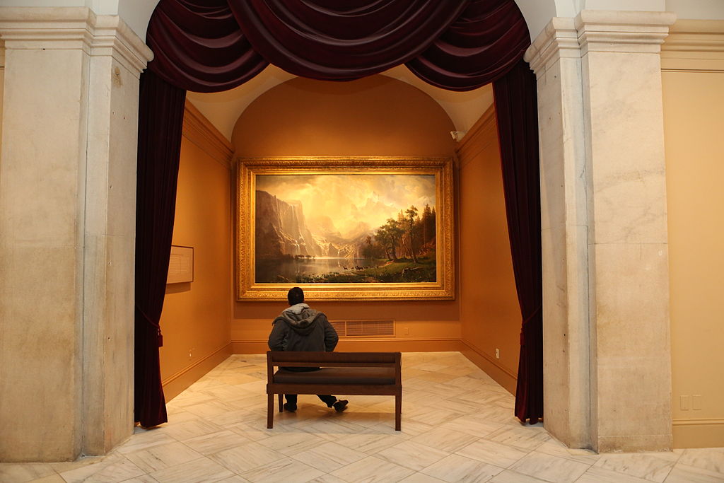 Seated person viewing painting in the second floor galleries at the Smithsonian American Art Museum