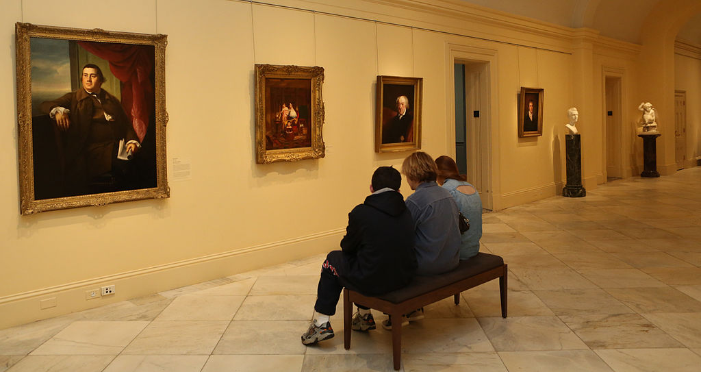 Three people seated on a bench on the second floor galleries at the Smithsonian American Art Museum