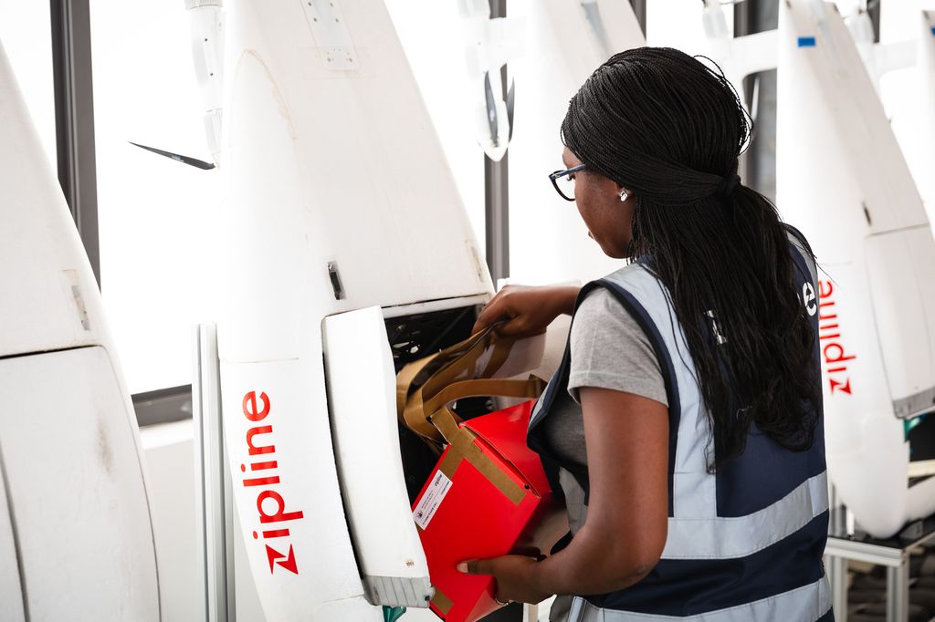 A woman places medical supplies into the "belly" of a drone.