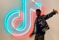 Lil Nas X in front of a neon sign at TikTok.