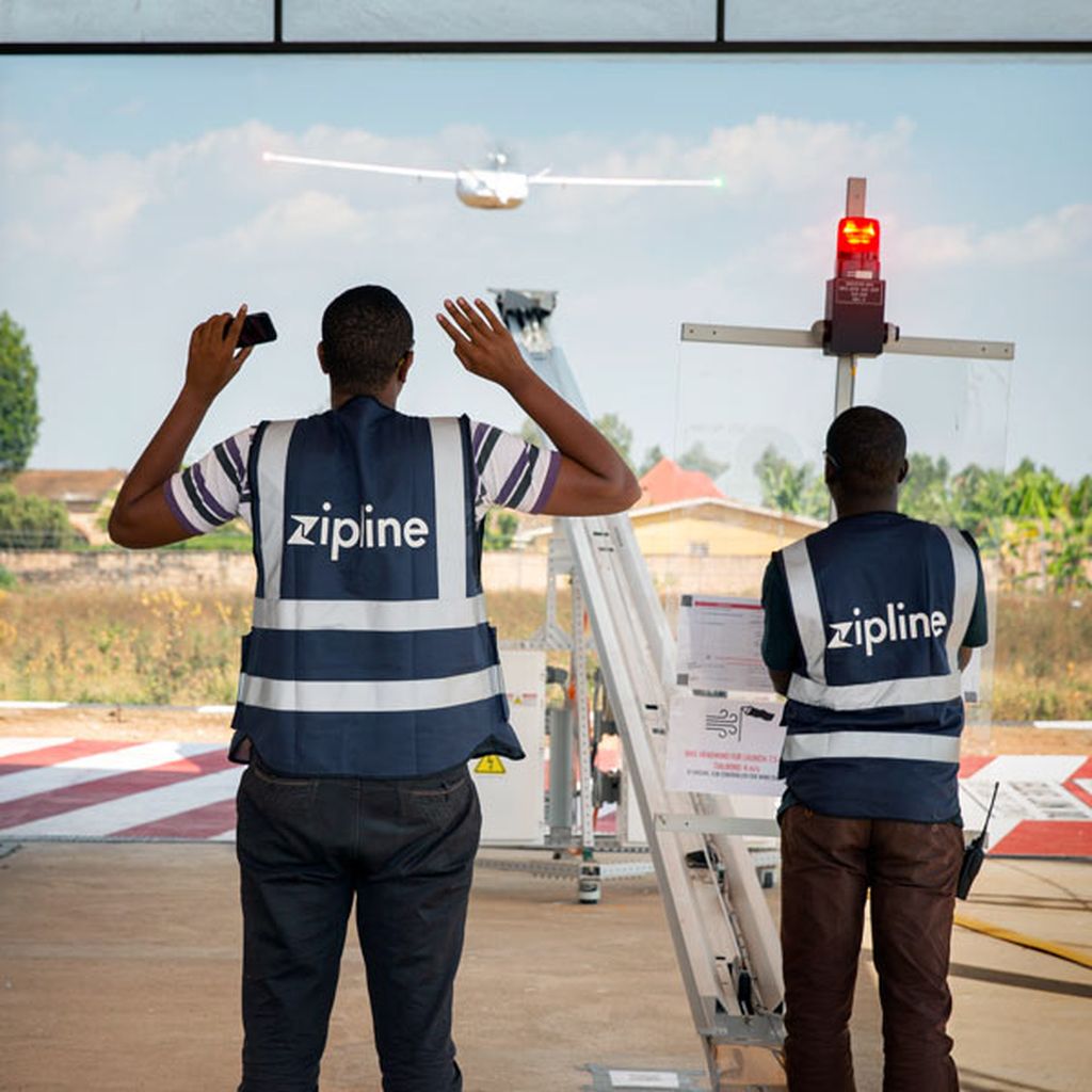 Workers watch as a drone takes off from a catapult.
