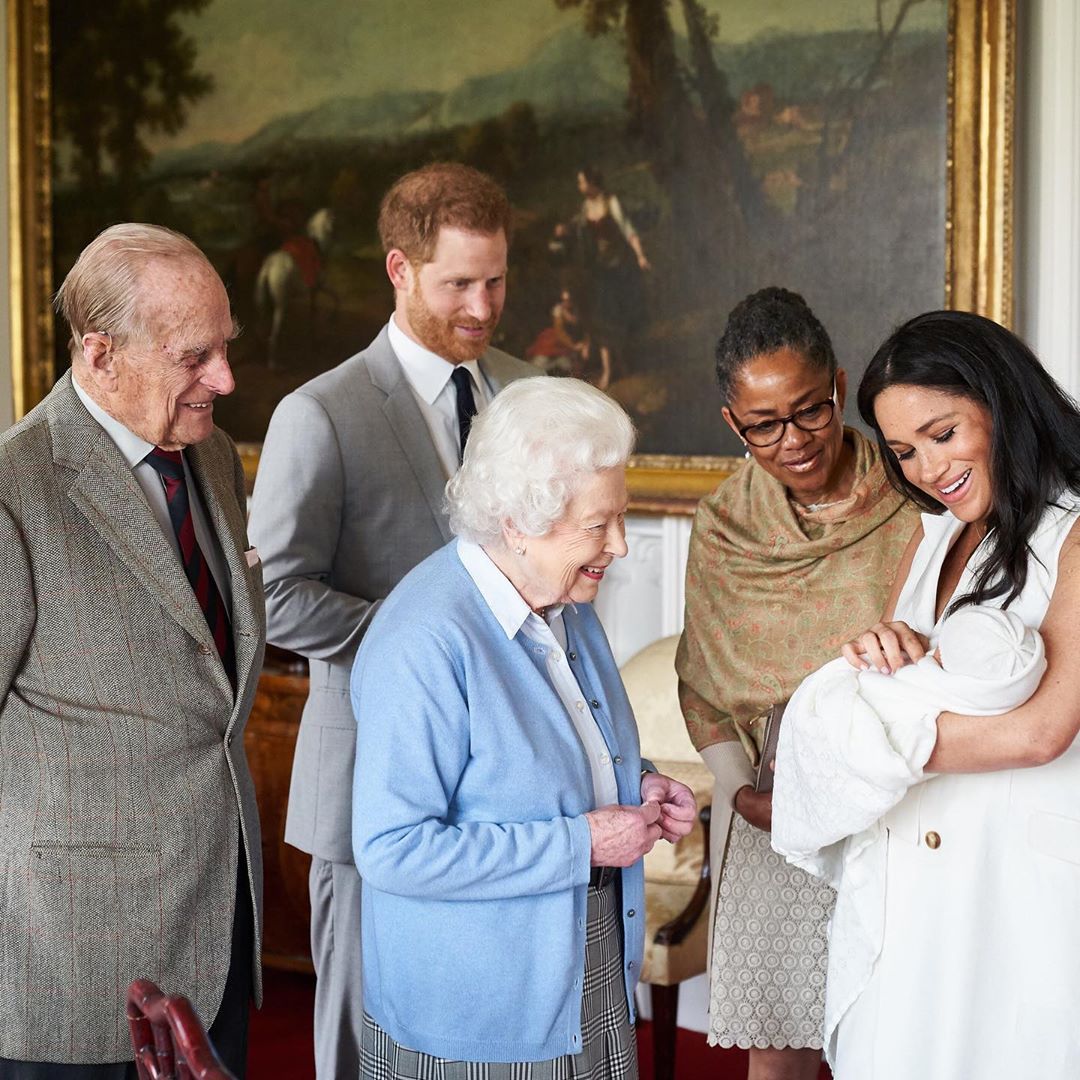 The Queen of England meets her great-grandson, held by his mother, Meghan Markle.