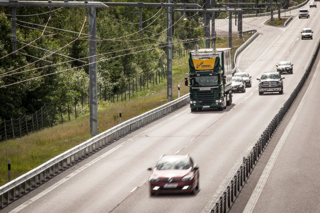 A hybrid truck travels on an eHighway, charging from an overhead cable system.