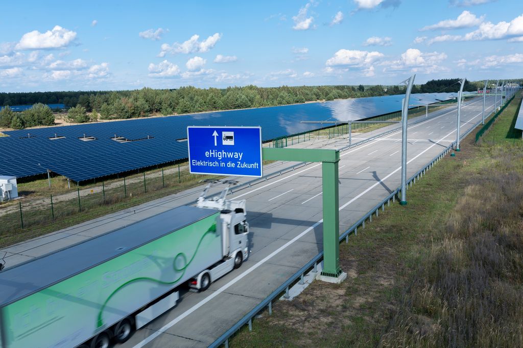 A hybrid truck travels on an eHighway, charging from an overhead cable system.