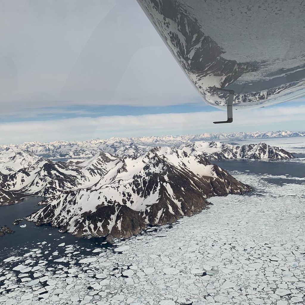 Wing of light sport aircraft over icy mountains.