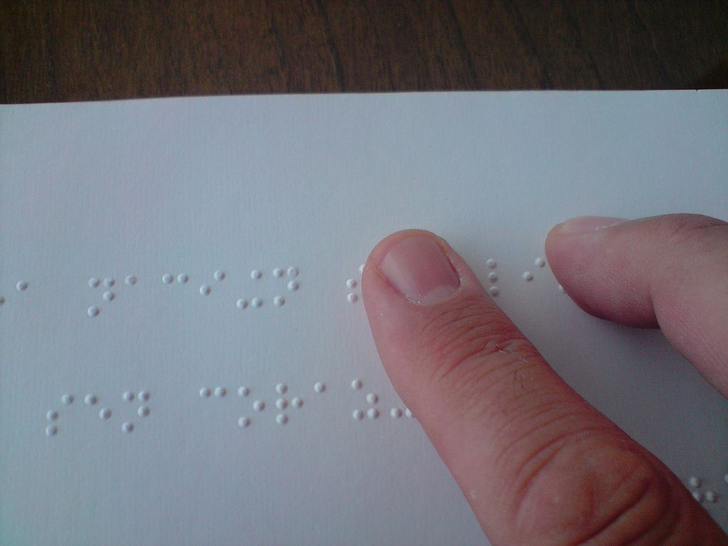 A person reading a braille book with two fingers