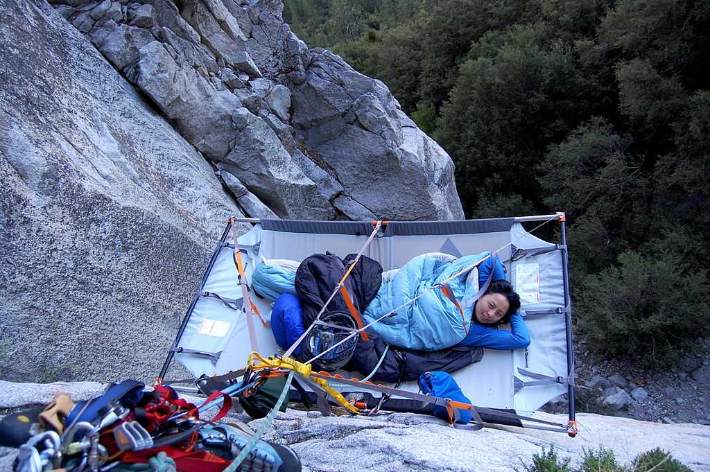 A woman lying on a portaledge.