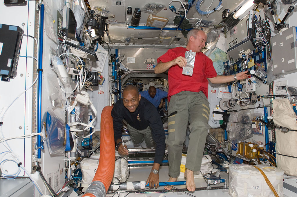 Astronauts Robert L. Satcher Jr. (left), STS-129 mission specialist; and Jeffrey Williams, Expedition 21 flight engineer, are pictured in the Harmony node of the International Space Station while Space Shuttle Atlantis remains docked with the station. Astronaut Leland Melvin, STS-129 mission specialist, is visible in the background.