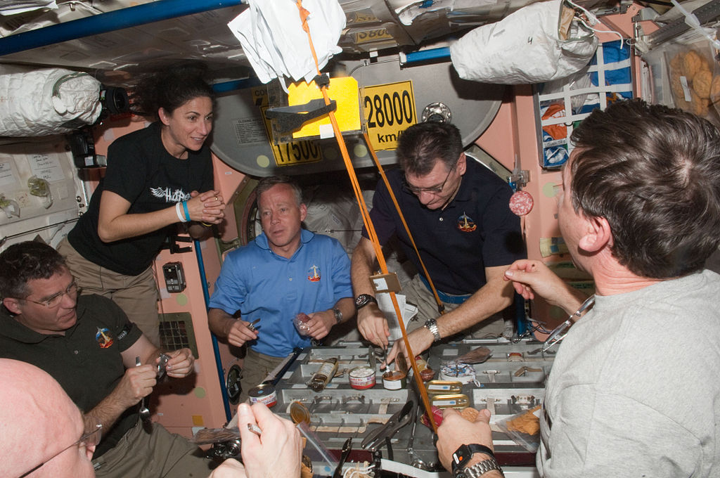 Expedition 26 and STS-133 crew members share a meal in the Unity node of the International Space Station while space shuttle Discovery remains docked with the station.