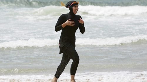 Woman in a burkini running on the beach