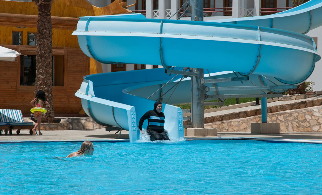 Woman in a burkini going down a water slide.