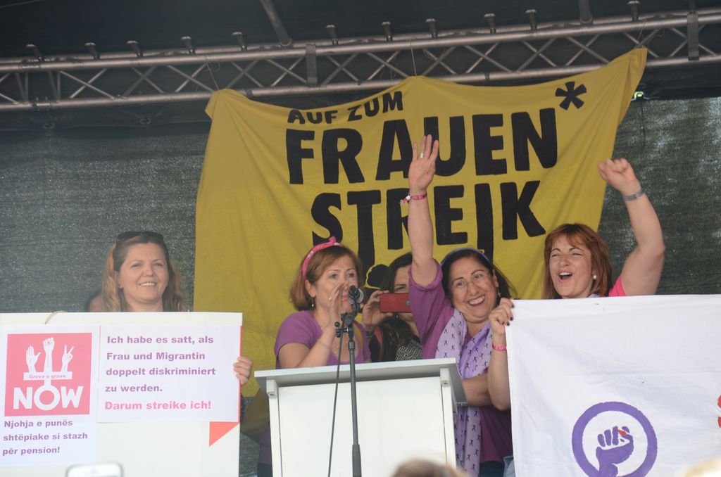 Women on a podium gesture at the Frauenstreik.