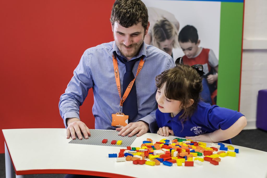 Teacher and student work with Lego's Braille bricks.